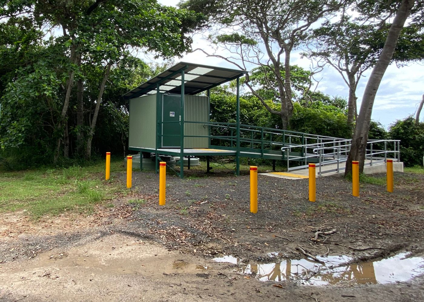 New Weary Bay Toilets new ramp accessible public toilet facility at Weary Bay in Cooktown. Green, corrugated, elevated, all-access toilet block and the ramp that leads up to it surrounded by safety bollards at weary bay